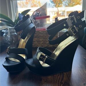 Black leather platform wedges with gold accessories.